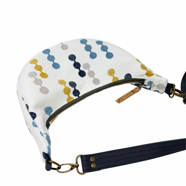 mmb by hand crescent crossbody bag in white textured fabric with navy, mustard, and grey geometric pattern